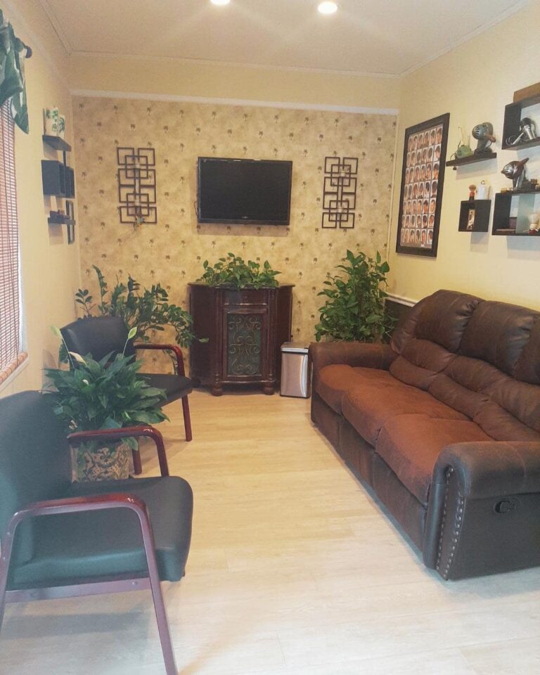 Photo of waiting room of Premos Barber Spa, contains a sofa and chair with wall decor.